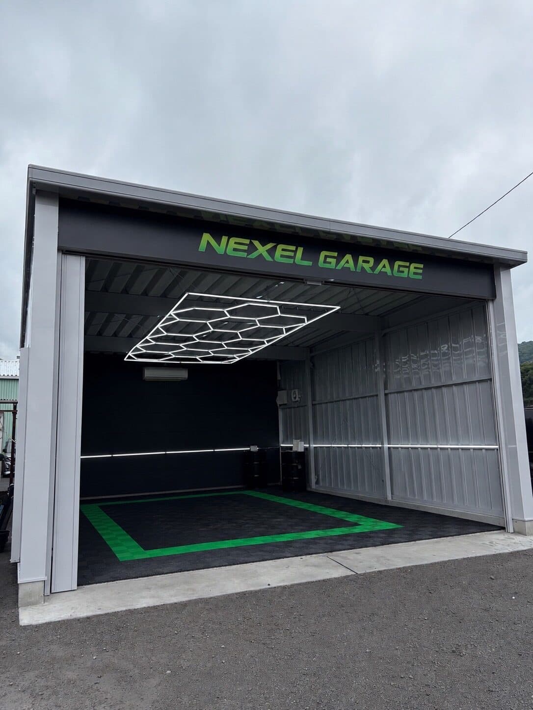 NEXEL GARAGE の施工ブース。天井にヘキサゴン型のLED照明を備え、床はブランドカラーのグリーンで縁取られている